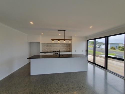 Polished concrete floor, Snowdrift puregrain cupboards with Silestone Arden Black benchtop
